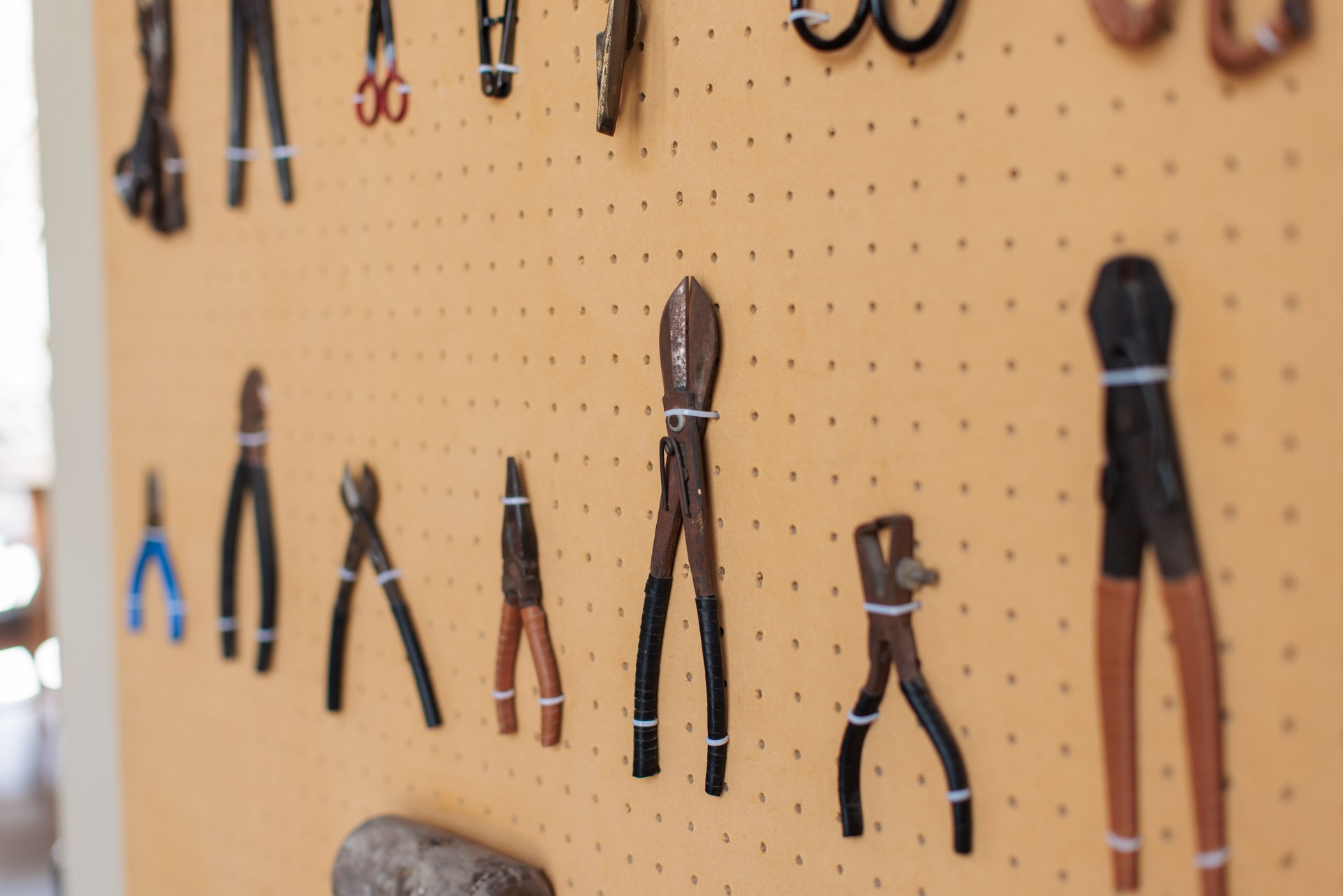 Variety of Pliers Hanging on Pegboard in Workshop